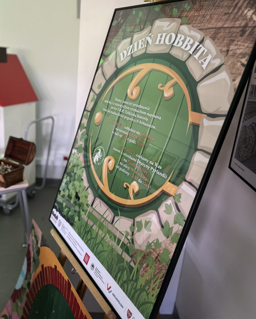 kolorowy plakat przedstawiający okrągłe wejście do domku hobbita