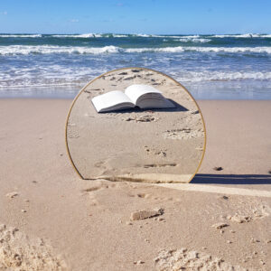 Książka leży na plaży nad wzburzonymi falami morza