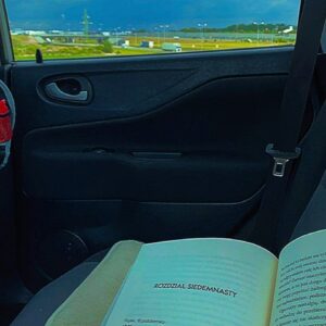 Książka w samochodzie, za oknem w tle autostrada