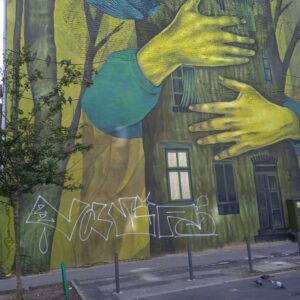 mural przedstawiający obejmowany rękami pień drzewa z drzwiami i oknami oraz ptaki