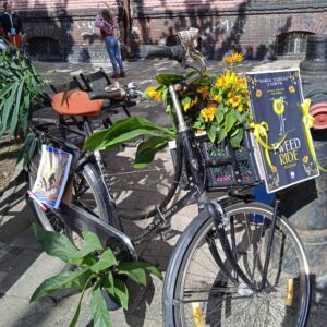 stojący na ulicy rower udekorowany kwiatami i liśćmi