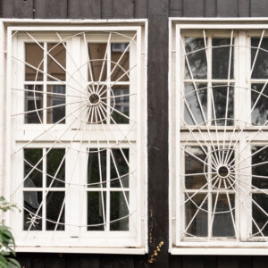 dwa stare okna z kratami w formie pajęczyn