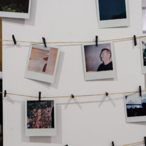 Zdjęcia wykonane aparatem Polaroid, powieszone na klamerkach, na sznurkach.